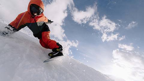 A snowboarder carves through the snow on a high performance snowboard.