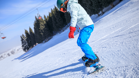 A snowboarder glides down a snowy slope on a performance snowboard