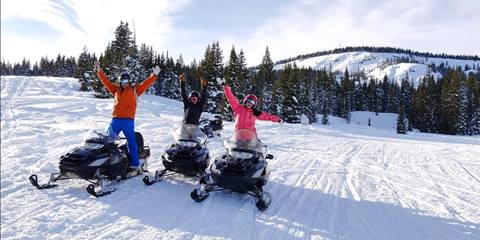 three people on snowmobiles