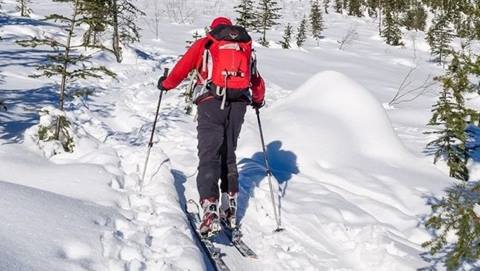 A man uphill skiing in the snow.