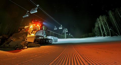 snow groomer at night