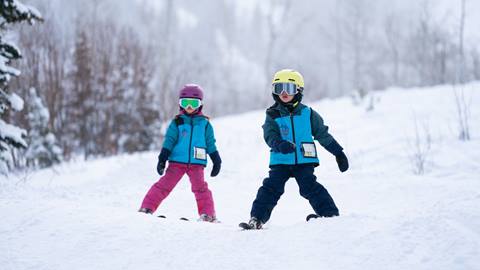two young skiers going down a trail