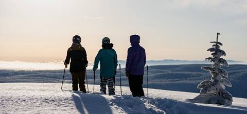 three skiers at sunset