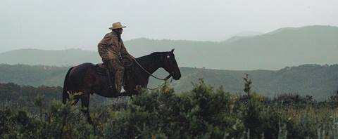 Cowboy riding his horse through the rain